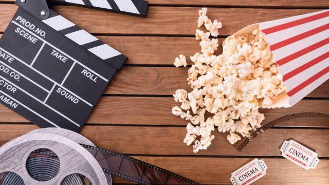 Clapper board, popcorn, film reel and cinema tickets on a wooden table